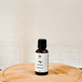 30ml Bottle of peppermint essential oil on a wooden paddle with a white textured background